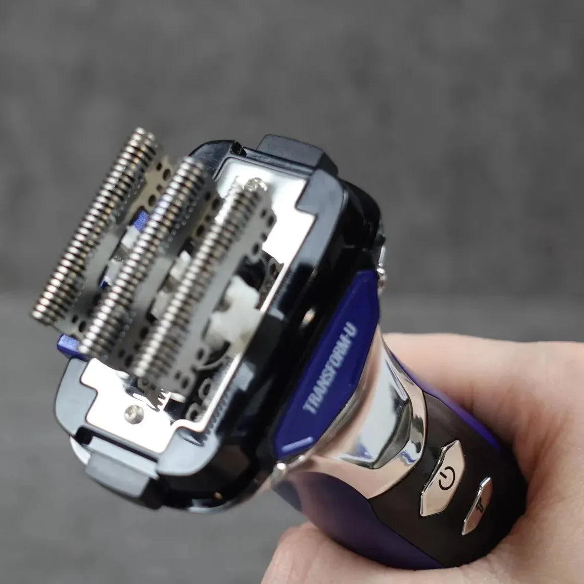 Hand holding a close-up of a blue electric shaver head, detached