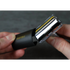 Close-up of a person holding a safety razor with a protective cover on a dark background