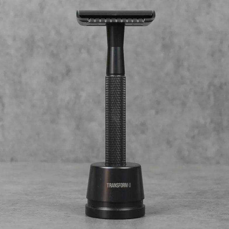 Black metal safety razor stand on a gray surface with a gray background
