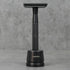 Black metal safety razor stand on a gray surface with a gray background