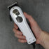 Hand holding a white hair clipper against a gray background
