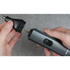 Person holding a black hair trimmer with a small attachment, against a gray background