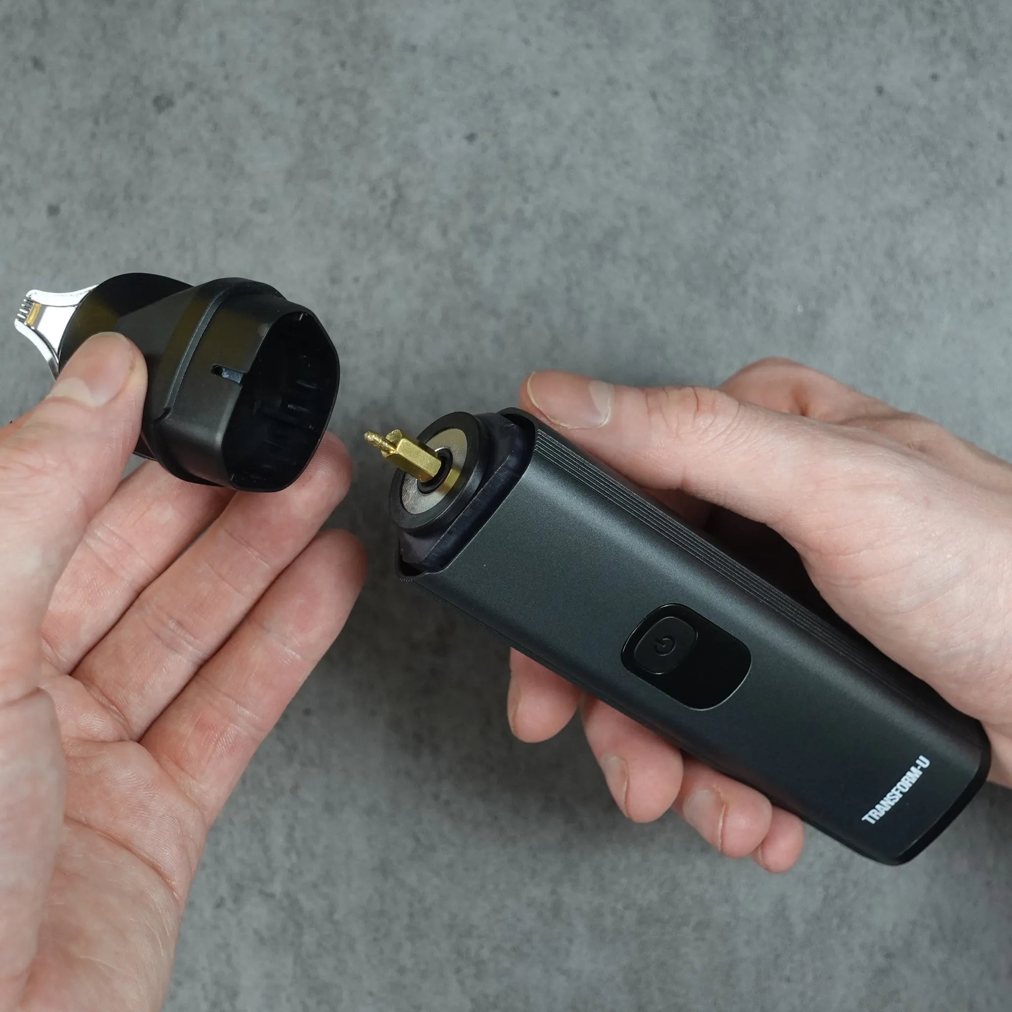 Person holding a black hair trimmer device with a gray background