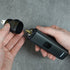 Person holding a black hair trimmer device with a gray background