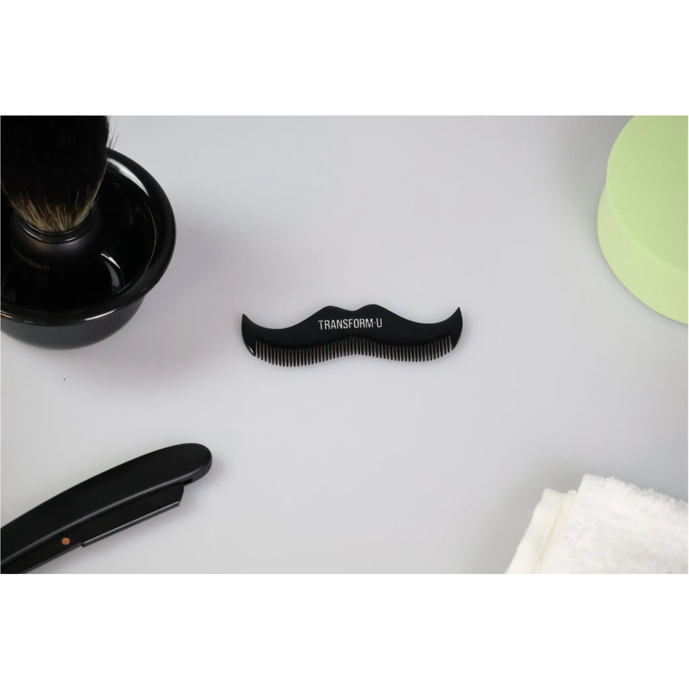 Black moustache comb with 'TRANSFORM U' branding on a white surface with grooming items.
