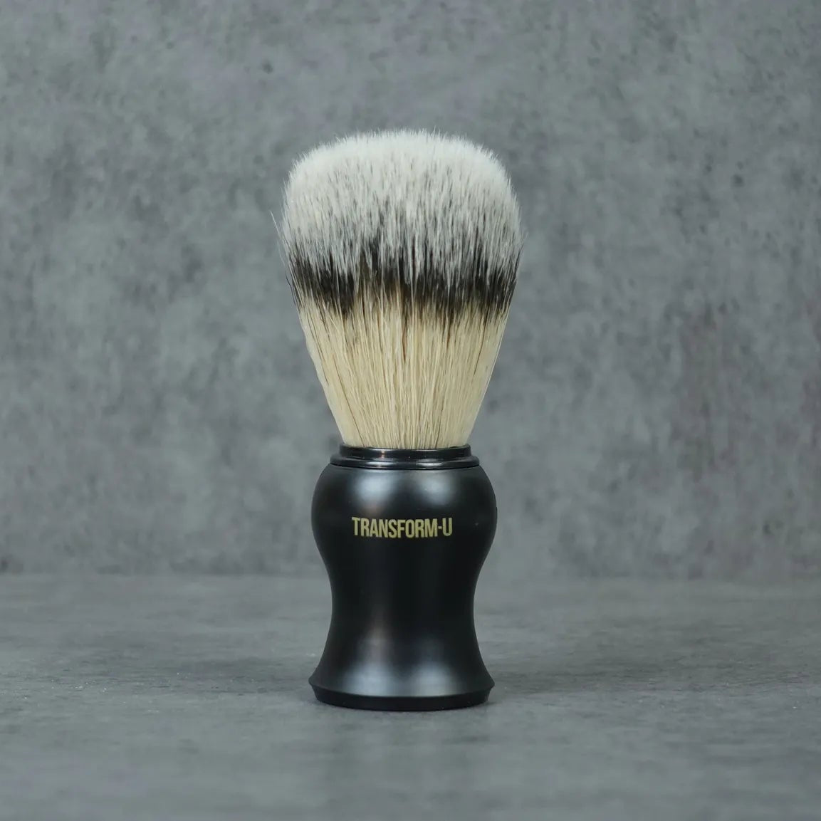 Shaving brush with black handle and white bristles on a gray background