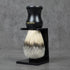 Shaving brush with black handle and stand on a gray background