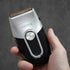 Hand holding a black and silver electric shaver against a dark background